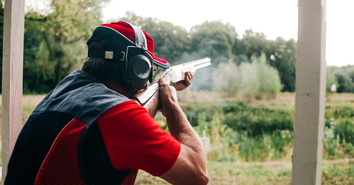 A man wearing hearing protection at an outdoor shotgun range