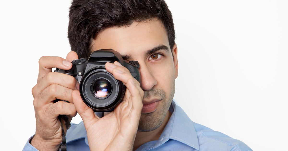 A photographer holding a camera in front of a light background