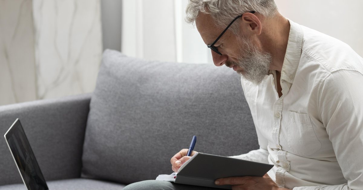 A man reviewing notes with a laptop at home