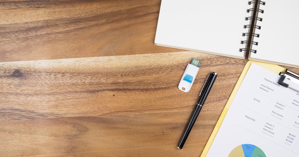 Documents, pens and a notebook arranged on a wooden desk