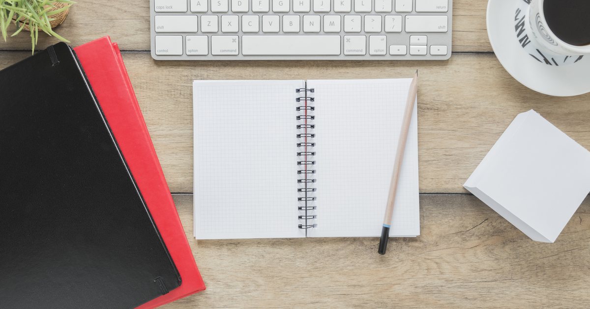 An open study notebook beside a keyboard and stationery