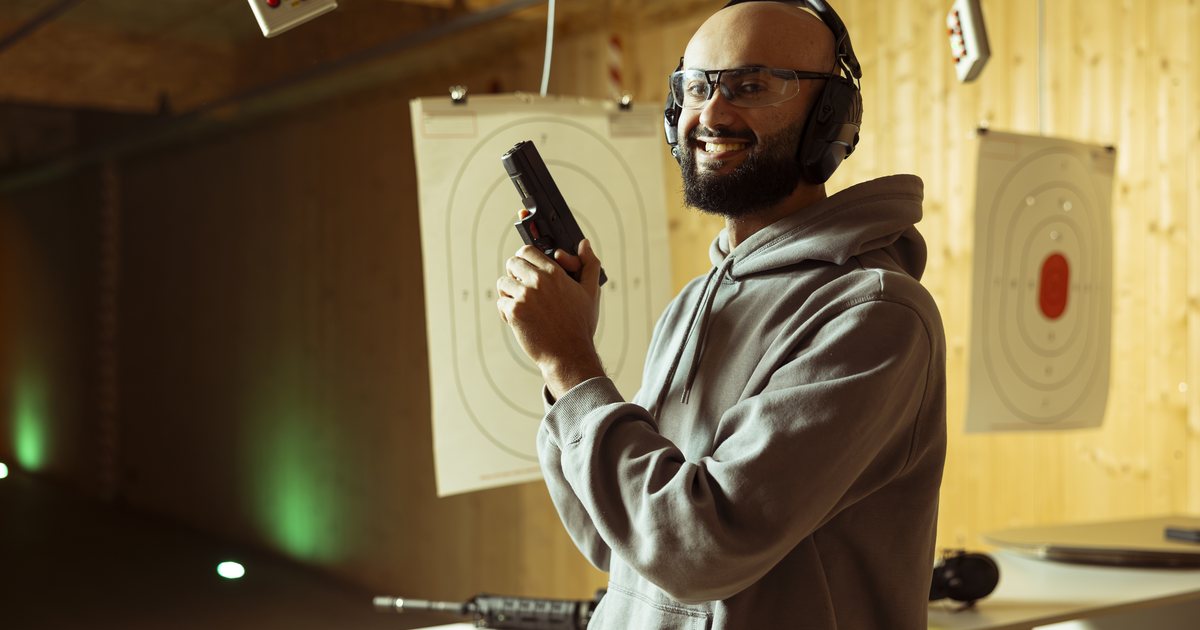 A man wearing protective glasses and earmuffs at an indoor range