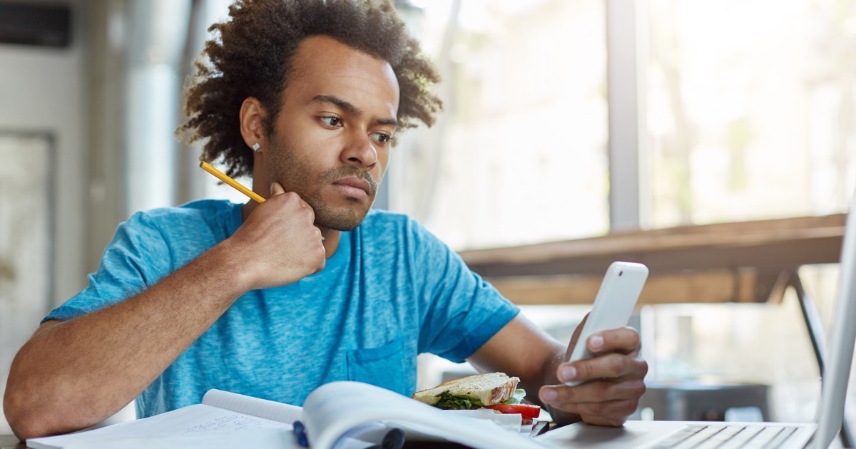 A man studying with a phone and an open notebook